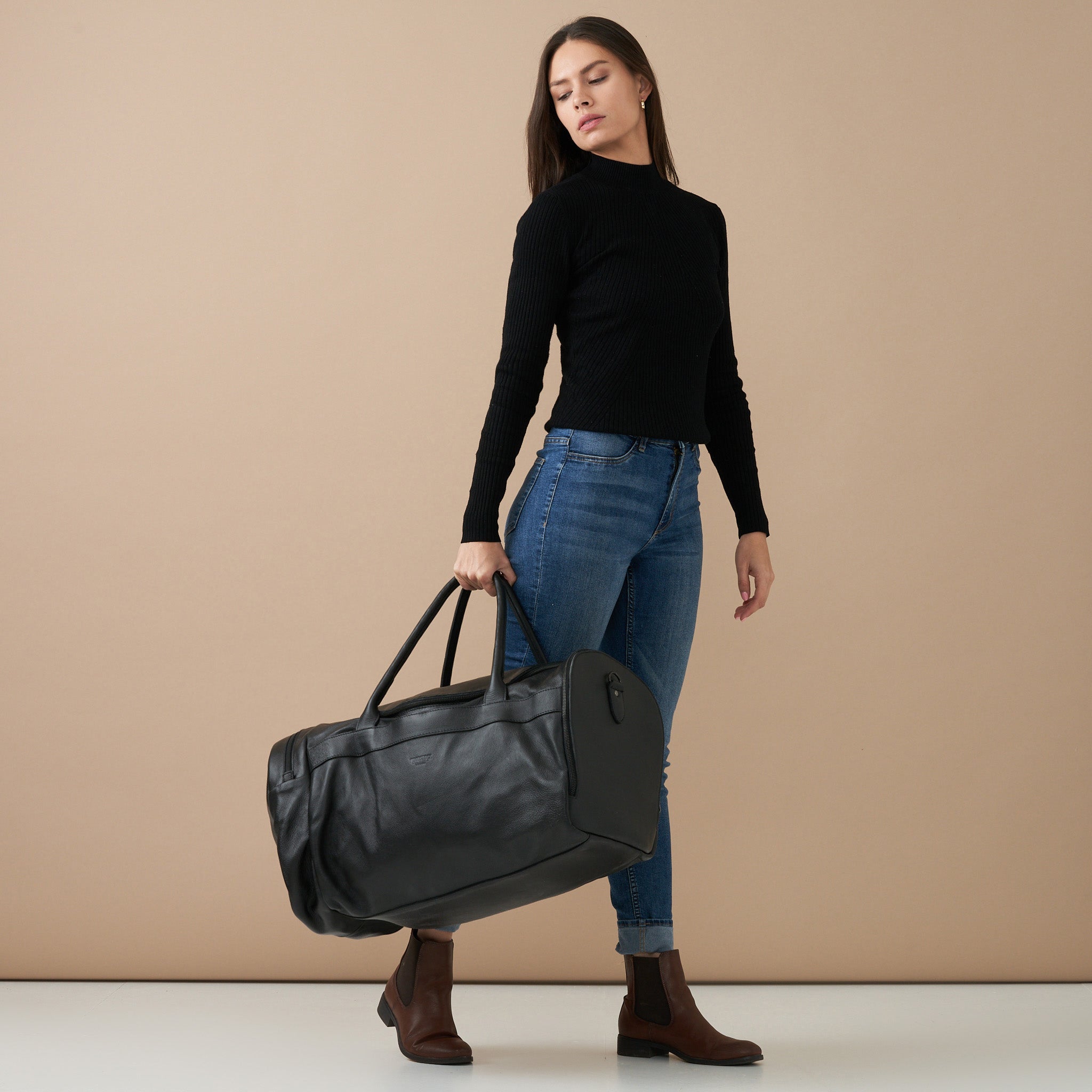 Model holding Black Genuine Leather Sports Duffel Bag with Waterproof Lining & Sneaker Compartment