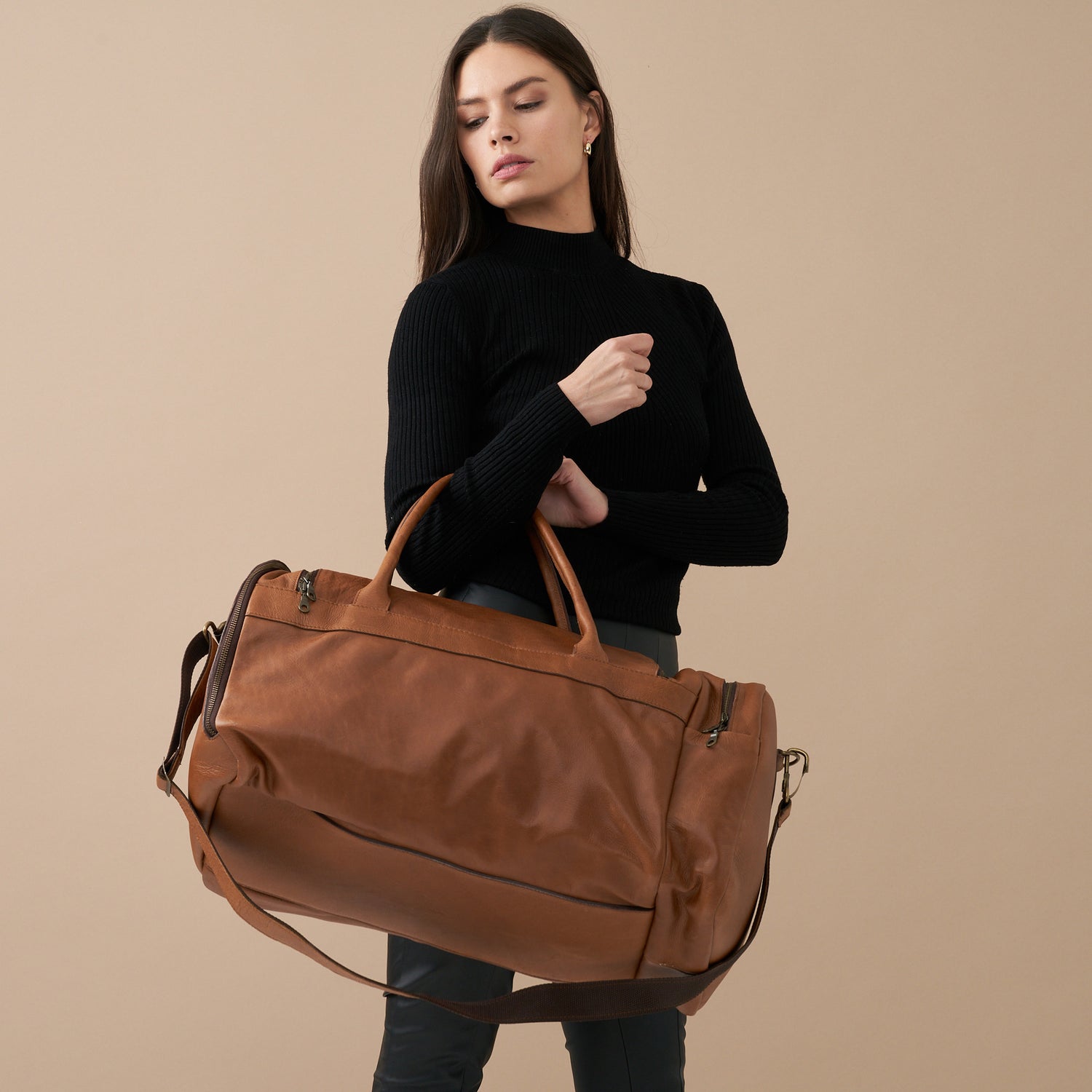 Model holding Pecan Genuine Leather Sports Duffel Bag with Waterproof Lining & Sneaker Compartment