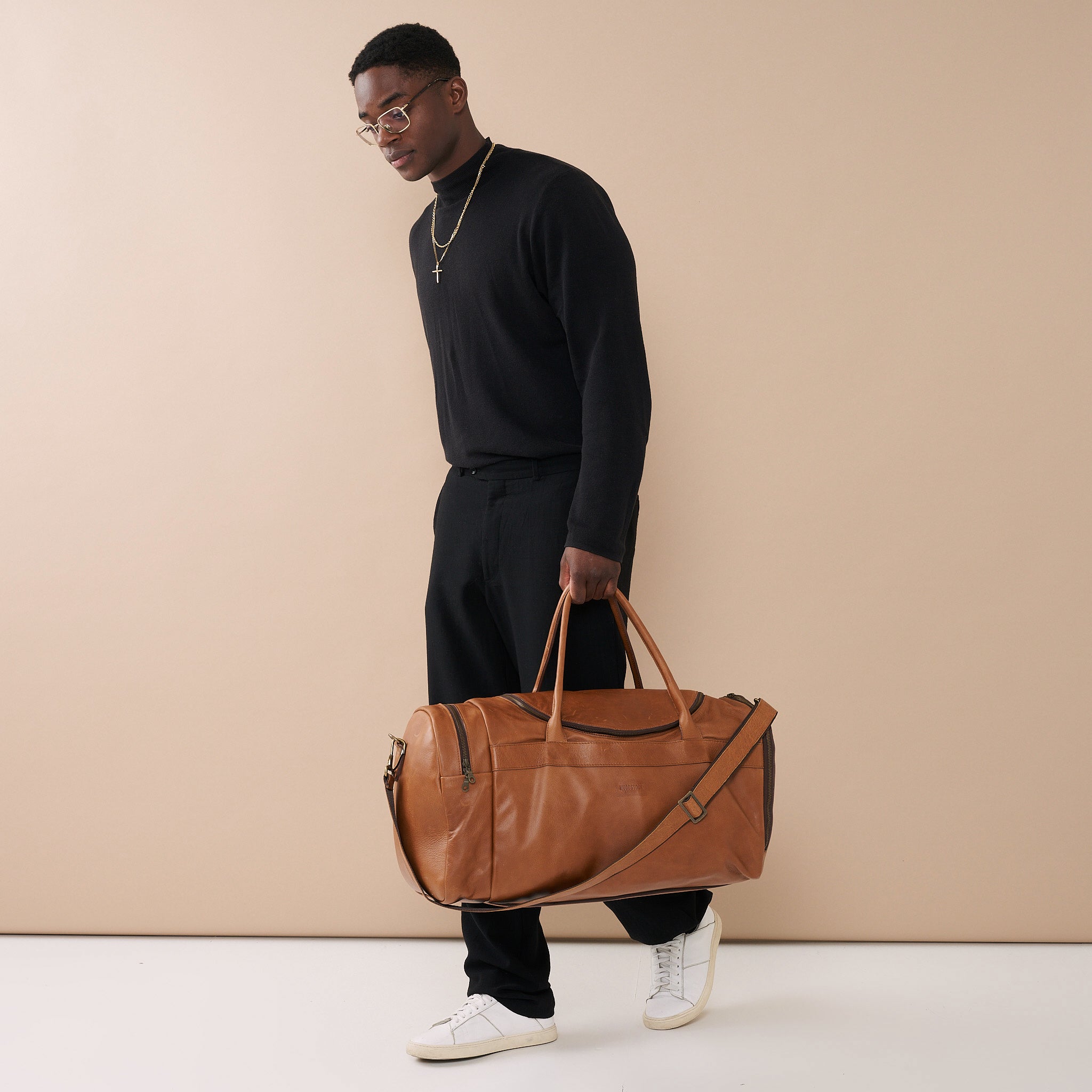 Model holding Pecan Genuine Leather Sports Duffel Bag with Waterproof Lining & Sneaker Compartment