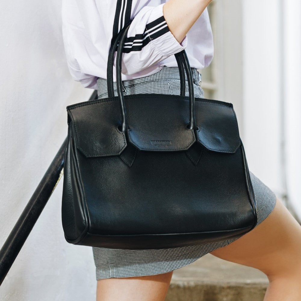 Woman holding Kate Handbag-Black by straps on her arm