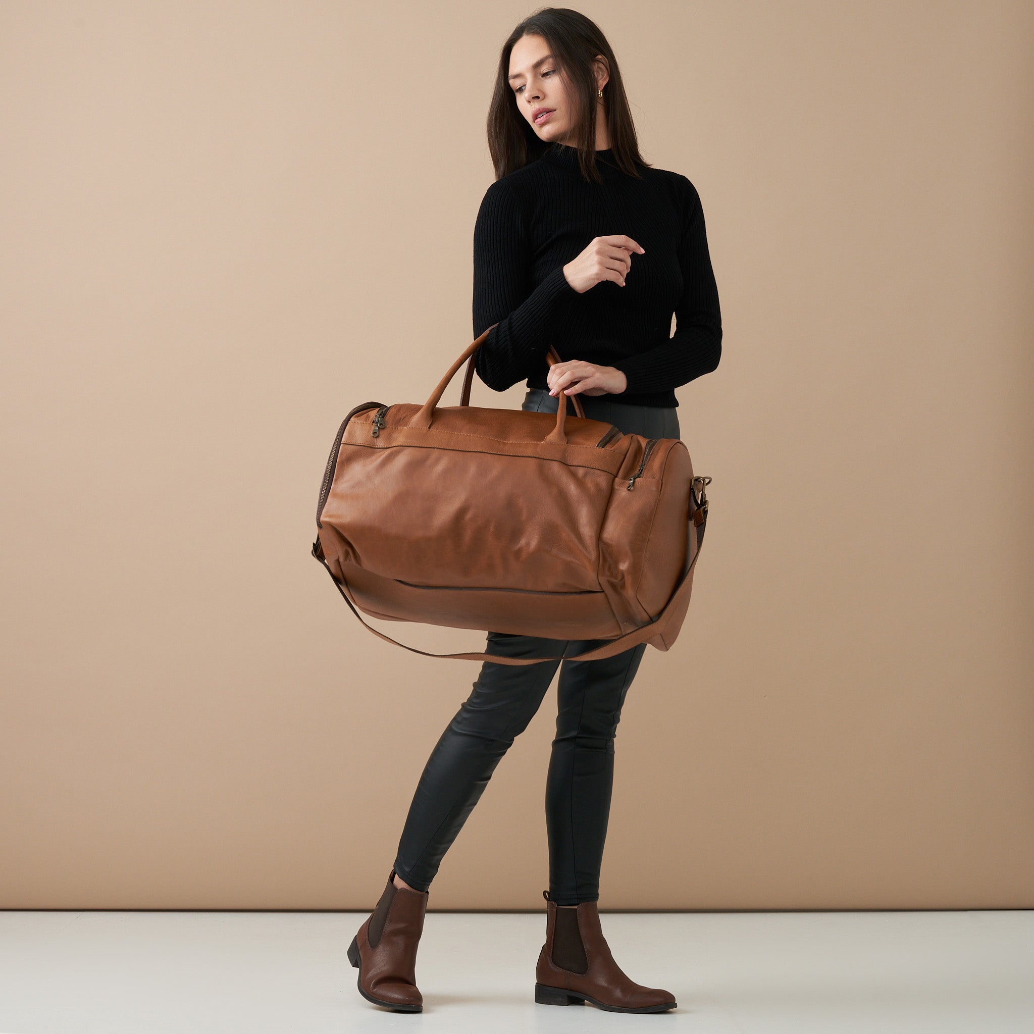 Model holding Pecan Genuine Leather Sports Duffel Bag with Waterproof Lining &amp; Sneaker Compartment